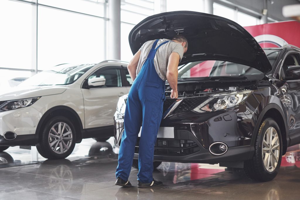 Mies tekemässä autohuoltoa ja tarkistusta